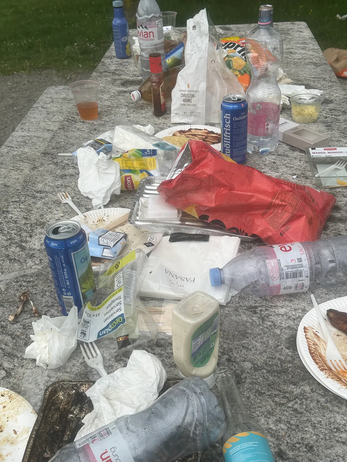 Man sieht diversen Abfall rund um eine Grill- und Feuerstelle.